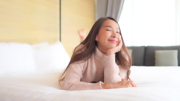 Asian woman relax on bed in bedroom interior