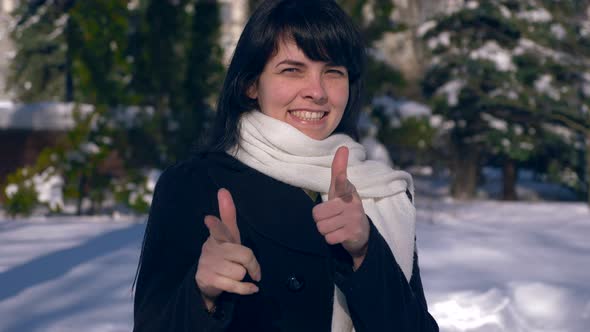 Beautiful Smiling Girl Makes Thumb Up Gesture. Snow Covered Park. Winter City