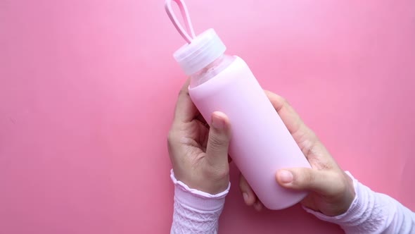 Hand Holding Sport Bottle Isolated on Pink, Top View .