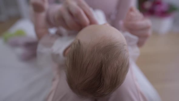 Head of Caucasian Infant with Blurred Woman Wiping Child Face