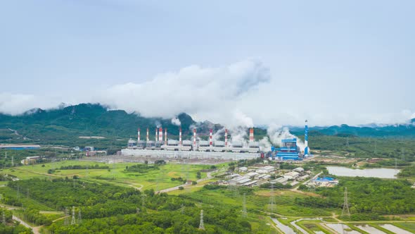 Aerial view over coal-fired power plant at sun dawn with smoke from cooling,