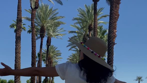 Asian woman walking down a palm tree lined path