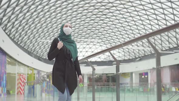 Pretty Muslim Woman in a Hijab with a Backpack and a Medical Mask on Her Face Goes Shoppingslow Mo