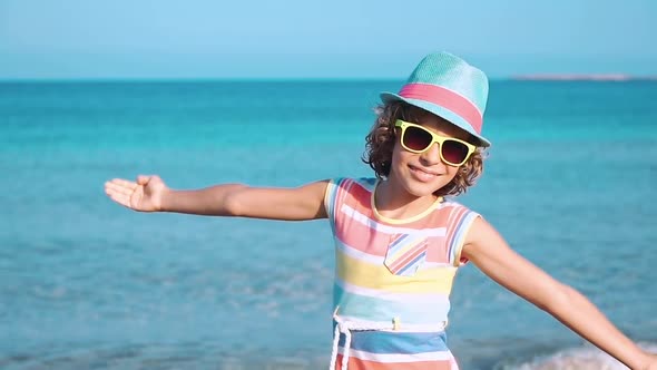 Happy Child with Open Hands against Blue Sea and Sky Background alt
