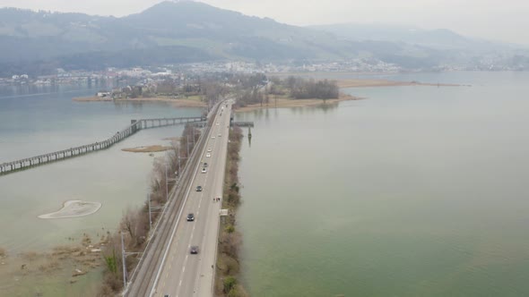 Aerial following a black car driving over the dam, Seedamm, Switzerland
