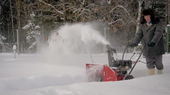 Man Cleans Snow With A Snow Plow On The Background Of The Forest In Winter