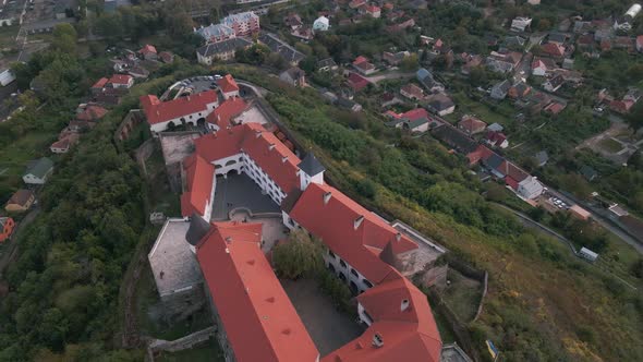 Drone Flies Over Medieval Castle on Mountain in Small European City at Cloudy Autumn Day