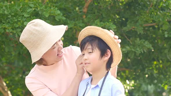 Asian Mother Put A Hat For Her Son On Summer Day