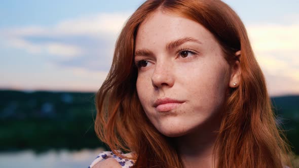 Red Haired Young Girl Posing on Background of the Lake Nature at Sunset