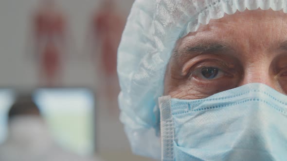 Close Shot of Mature Surgeon in Facial Mask Smiling at Camera