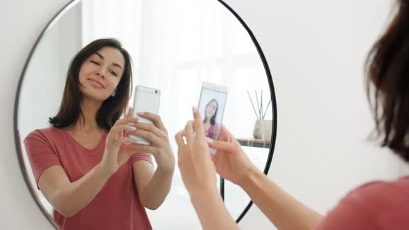 Slow Motion of Beautiful Woman Taking Selfie in Bathroom in Front of Mirror Using Smartphone