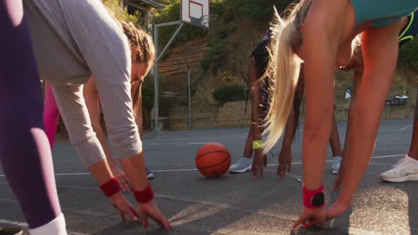 Diverse female basketball team wearing sportswear, stretching