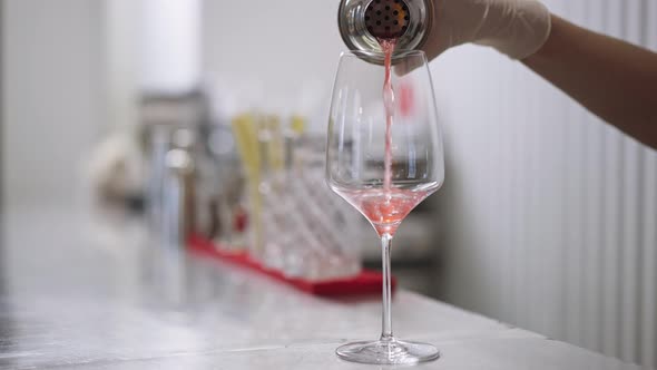 Closeup Pouring Pink Orange Cocktail From Shaker in Drinking Glass in Slow Motion