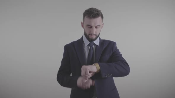 Portrait of Handsome Caucasian Businessman in Elegant Suit Looking at Time and Tapping on Watch Face