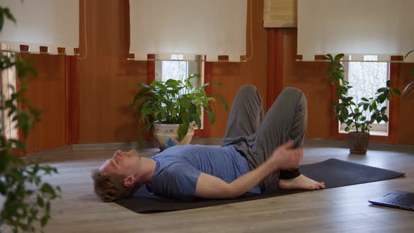 Wellness Young Man Doing Yoga in Room at Home Man Performs the Bridge Pose Near Windows