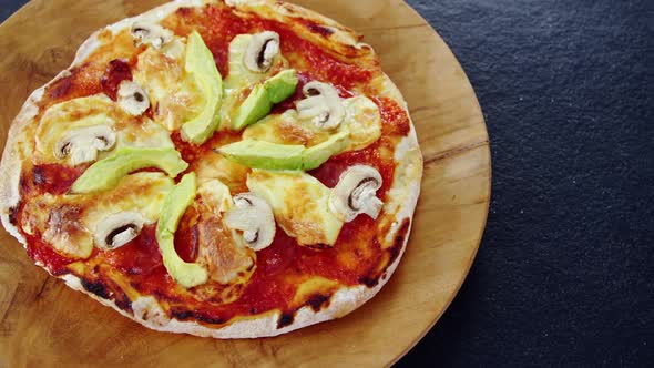 Baked pizza with avocado and mushroom toppings