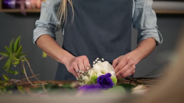 Closeup View of Hands of a Flower Shop Assistant Tying a Bunch of Flowers Lying on Her Table with