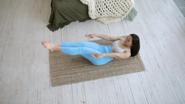 Young Woman in Sportswear Is Pumping the Abdominals Pulling Legs To Chest