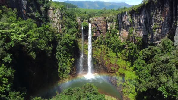 Drone shot of Mac Mac Fall in South Africa - drone is reversing from the waterfall, showing a rainbo