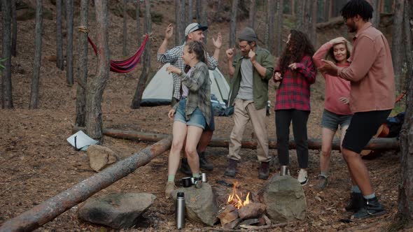 Slow Motion of Carefree Youth Tourists Dancing in Campsite in Forest Around Fire Enjoying Nature and