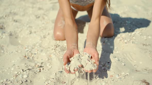CLOSE UP Unknown Playful Young Woman Throws a Handful of White Sand Over the Camera