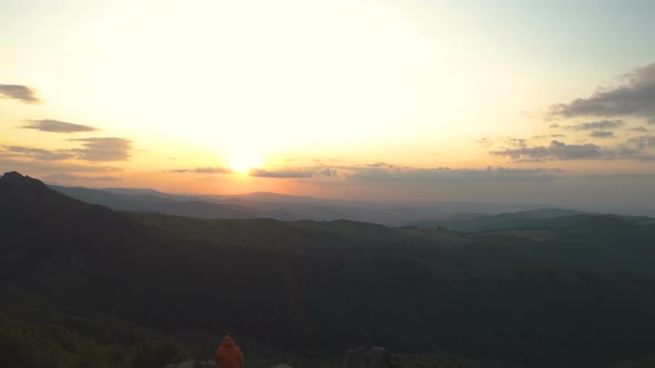 Mountain Hiker with Map Taking Rest at Sunset Sitting on Mountain Peak and Enjoying the Sunset