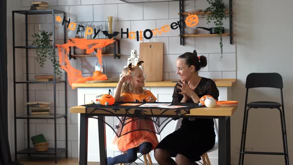 Woman with Daughter Playing Halloween Board Game