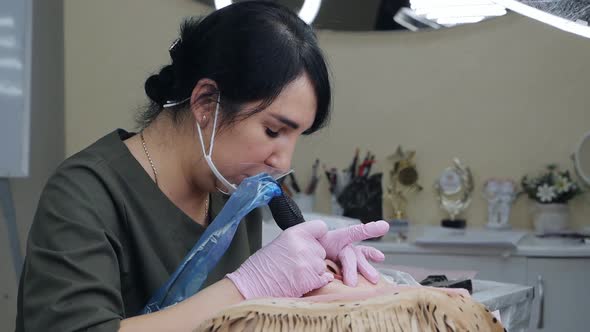 Cosmetologist Applies Permanent Pigment Tattoo to Female Lips with Tattoo Needle in Salon