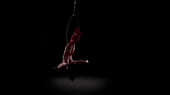 Girl Athlete Performs Acrobatic Stunts on the Air Hoop. Black Background. Slow Motion