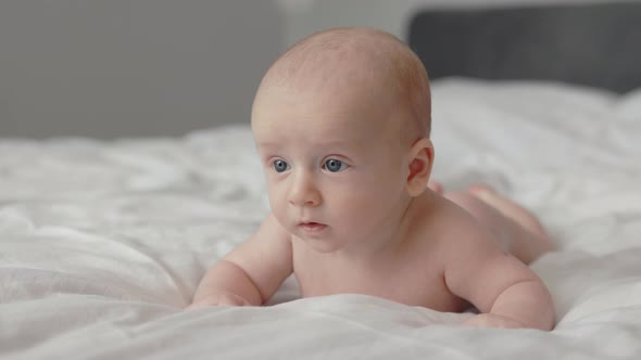 Close Up of Pretty Infant Lying on Bed on His Stomach