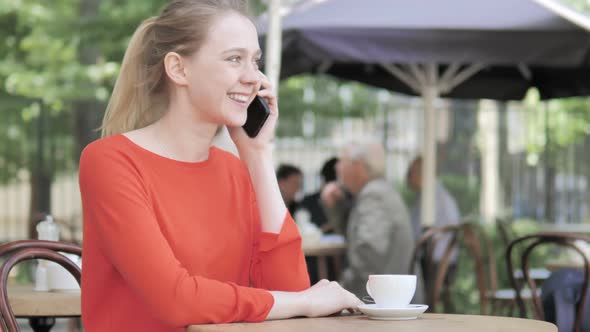 Young Woman Talking on Phone, Sitting in Cafe Terrace