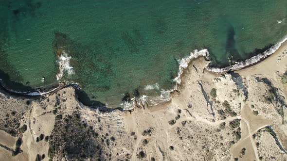 Slowly circling toward rocky Mediterranean coastline with turquoise blue water. Summertime Milos Gre