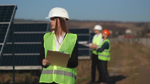 A Female Engineer is Examining Solar Panels and Recording Data