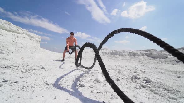 Bodybuilder exercising with battling ropes