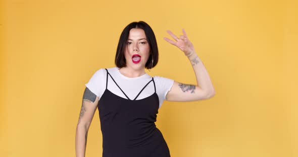 Hipster unusual woman with tattoo dancing funny on a yellow background