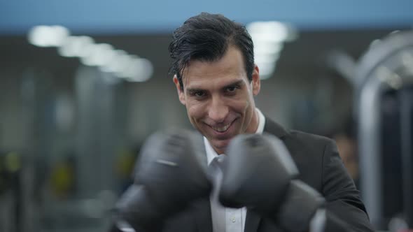 Closeup Portrait of Smiling Happy Confident Man in Formal Suit and Boxing Gloves Posing in Gym