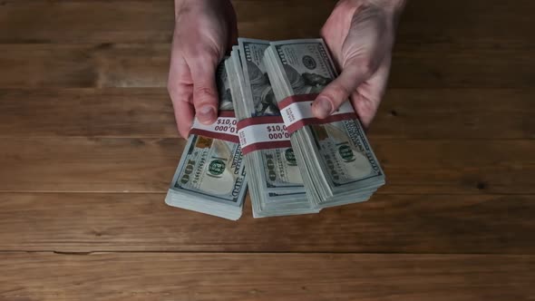 Male Hands Flipping Stacks 10000 Dollar Bills on Wooden Background Slow Motion