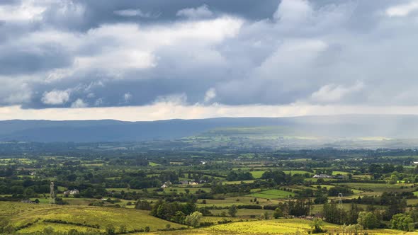 Time lapse of rural farming landscape with grass fields and hills during a passing storm rainy day i alt