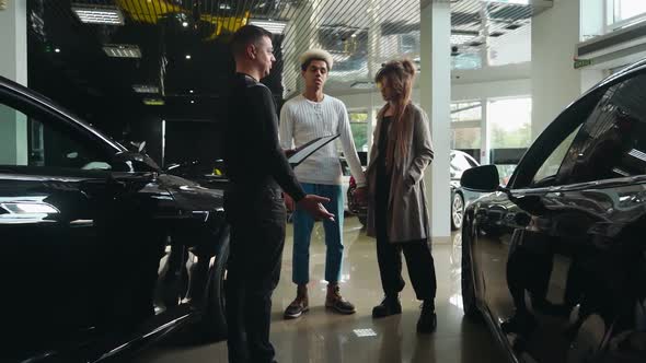 Multiracial Couple Consulting with Salesman About New Car