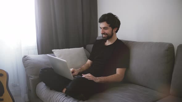 Happy Man Relaxing on Couch While Video Calling Using Laptop at Home