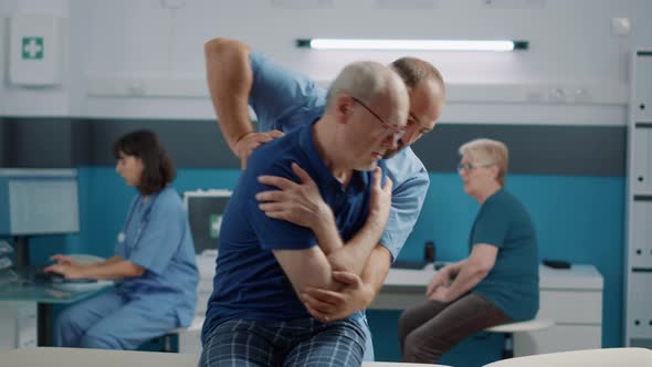 Physiotherapist Helping Senior Man to Crack Back Bones