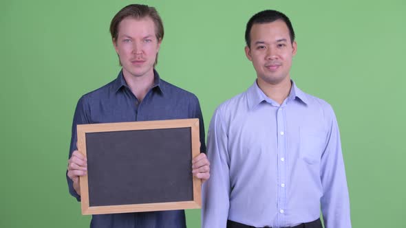 Two Happy Multi Ethnic Businessmen Holding Blackboard and Giving Thumbs Up