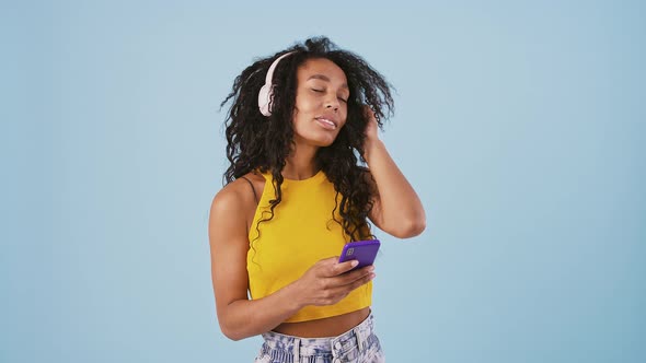 Afroamerican Woman is Smiling Dancing Listening to the Music Through Headphones and Looking at Her