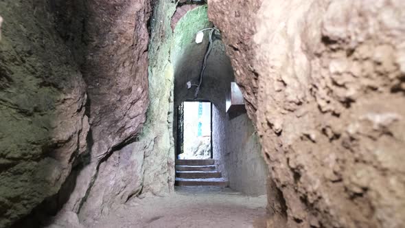 The cave is illuminated by a lantern light. Speleology, dark underground excavation tunnel.