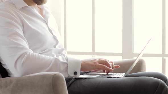 Hands of Businessman Typing a Message on Laptop Working in Office Near Window