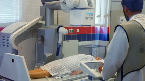 Male doctor sets up the machine to x-ray a female patient