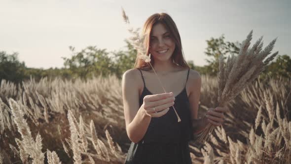 Beautiful Young Woman Walks in the Field Collects a Bouquet of Flowers and Spikelets