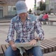 Caucasian Man Sitting on a Bench in a Square in the City Studying a Map of City - VideoHive Item for Sale