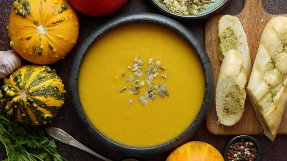 Homemade Vegetarian Pumpkin Cream Soup Served in Ceramic Bowl. Decorated with Seeds