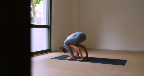 Cheerful sportswoman improving concentration while doing Tittibhasana yoga pose